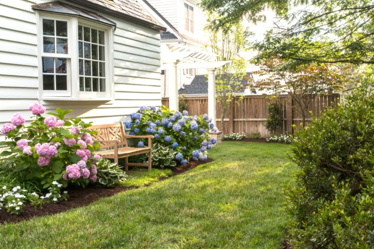 white house with backyard bench in the middle of flowers