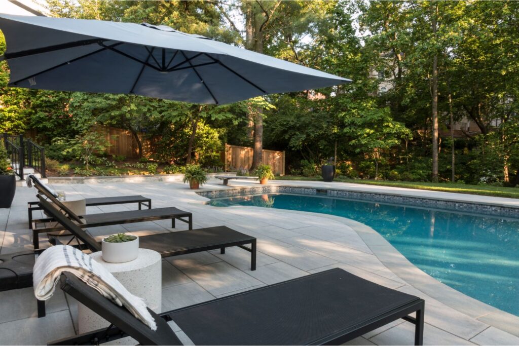 Modern chaises and an umbrella sit aside northern Virginia pools cape